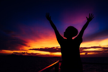 Fototapeta premium silhouette of a girl with hands up. on sunset background