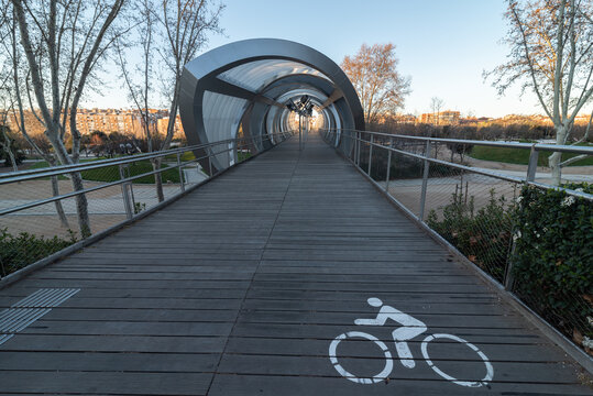 Perspective view of paved wooden bike path going to futuristic gallery in park in city during evening