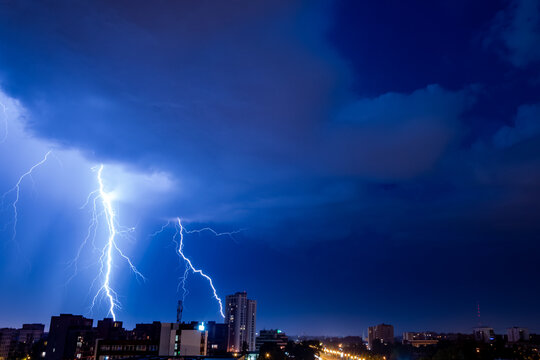 Bright flash of powerful lightning in the city at nighttime.