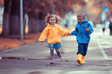 children run in the yellow autumn park rain / fun walk autumn seasonal landscape weather wet