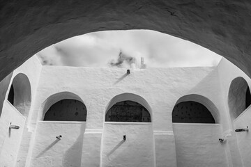 Exterior of minimalist walls with arches in ancient city of Izamal against cloudy sky