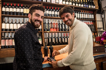 Smiling customer card paying in market wine house.