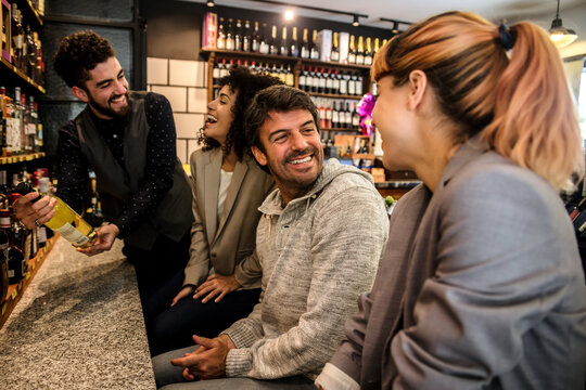 Group of people gathering in market wine house for tasting wine sorts and laughing happily.