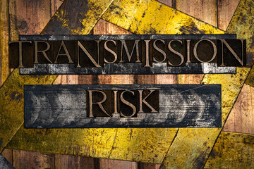 Transmission Risk text formed with real authentic typeset letters on vintage textured silver grunge copper and gold background