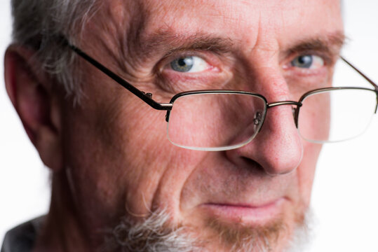 Older Man In 40s 50s Or 60s With Gray Grey Hair And Beard Or Goatee Looking Over Rim Of Eye-glasses With Suspicious Look In Eyes, Tight Crop Close-up Portrait.