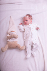 Portrait of a child on a white background with plush bear toy. Baby girl 1 months among toys. Space for text.