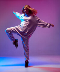 Stylish young girl, cool dancing in a hoodie with developing hair, on a neon background. Dance school poster