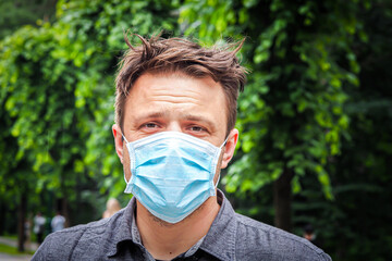 Handsome young European man smiling with a medical face mask on. Closeup of a 35-year-old male in a respirator to protect against Covid-19