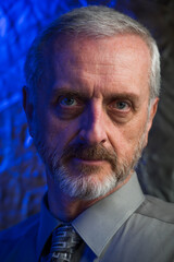 Old man in his 50s or 60s with gray hair, beard, shirt and tie with piercing stare and dramatic...