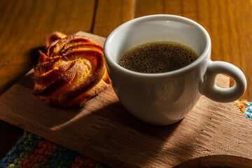 Café com espuma em xícara branca e broa de milho.