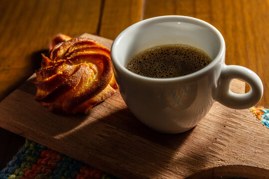Caf&eacute; com espuma em x&iacute;cara branca e broa de milho.