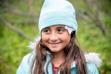 Cute young girl weraing hat during a cold day outdoor. Smiling to someone