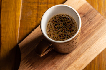 Xícara de cerâmica com café sobre mesa de madeira.