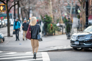Fototapeta na wymiar Back view of beautiful blonde business woman walking along New York City street