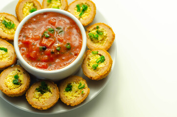 Mini scotch eggs with tomato sauce served on the white ceramic plate