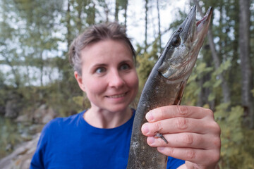 Young excited woman fishing a pike outdoor in Russia