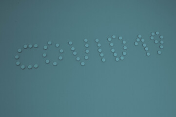blue tablets are laid out in the form of letters coronavirus 2019. volumetric inscription on a muffled blue paper background, shot from above. pills spilled from a jar, the name of a pandemic