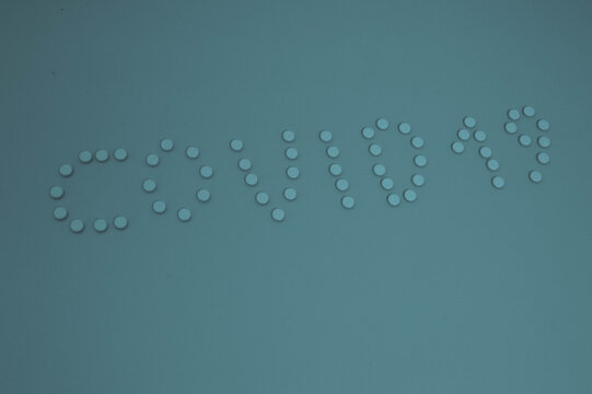 blue tablets are laid out in the form of letters coronavirus 2019. volumetric inscription on a muffled blue paper background, shot from above. pills spilled from a jar, the name of a pandemic