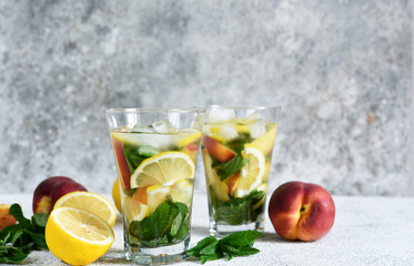 Lemonade with peach and mint in a glass cup on a concrete background. Peach lemonade.
