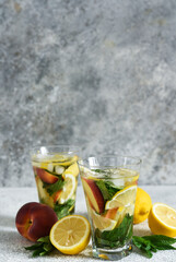 Lemonade with peach and mint in a glass cup on a concrete background. Peach lemonade.