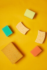 Image of different colorful sponges for housework isolated on yellow background