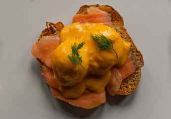 Delicious eggs Benedict with smoked salmon, hollandaise sauce and parsley.