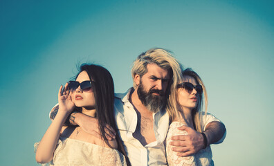 Young people friends of two pretty cute sexy girls or women and bearded man outdoors in park on...