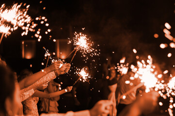 festive burning bright sparklers in the hands of guests at a party. New Year or wedding...