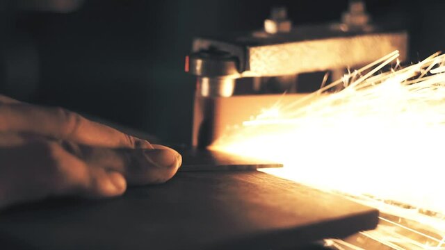 Man sharpening knife with sparks. Work on a sharpening machine