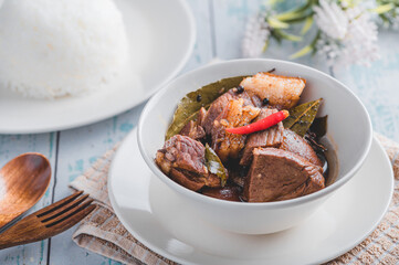 Pork Adobo (Side with Rice) is a Filipino dish stewed in vinegar, garlic, onion, soy sauce, bay leaves,  and peppercorns .