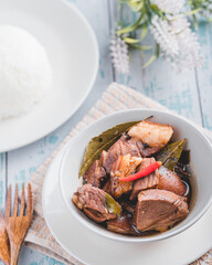 Pork Adobo (with rice) is a Filipino dish stewed in vinegar, garlic, onion,  soy sauce, bay leaves, peppercorns .