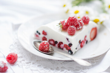 Dessert of yogurt , berries and gelatin, decorated with raw raspberries and natural red rose in white background, fresh, healthy food  