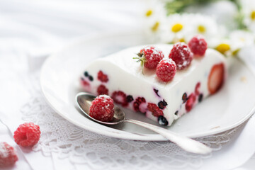 Dessert of yogurt , berries and gelatin, decorated with raw raspberries and natural red rose in white background, fresh, healthy food  