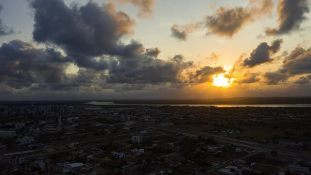 Beautiful aerial drone time-lapse shot of a golden vivid sunset with the small tropical town of Cabedelo, a large amazonian river, and forests below near Joao Pessoa in Northern Brazil.