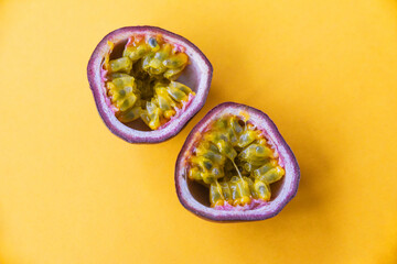 two halves of passionfruit close-up on a yellow background. tropical fruits