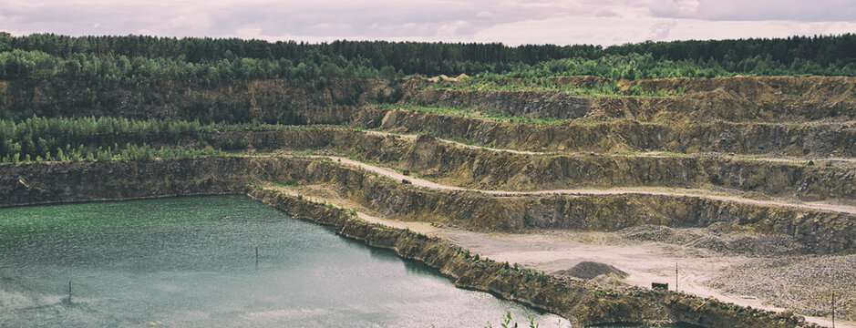 The huge open-cast quarry with lots of snones and water inside