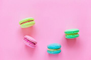 Sweet almond colorful pink blue yellow green macaron or macaroon dessert cake isolated on trendy pink pastel background. French sweet cookie. Minimal food bakery concept. Flat lay top view, copy space