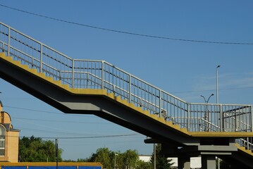 gray concrete footbridge with iron handrails against a blue sky