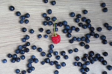 scattered ripe, large blueberries around, raspberries. Dark gray table, top view