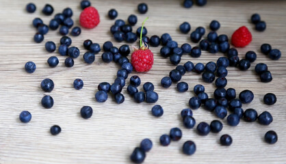 scattered ripe, large blueberries around, raspberries. Dark gray table, top view