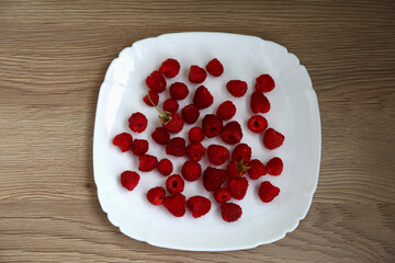 Ripe, delicious raspberries laid out on a plate, close up
