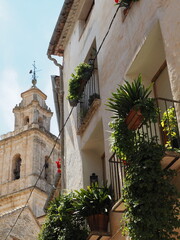Torre de la Iglesia junto a edificio con balcones y plantas en Bocairent, Comunidad Valenciana | Spanish townhouse with balconies and plants next to medieval church tower 