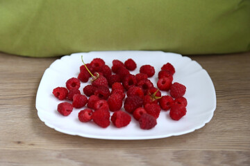 Ripe, delicious raspberries laid out on a plate, close up