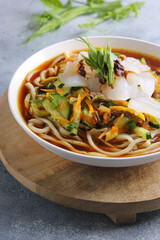 Eastern oriental cuisine, Asian cuisine. Cold soup ashlam fu. Soup with noodles, starch and vegetables. Spicy soup on a light grey background and in a white plate. Background image, copy space