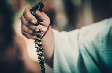 male monk holds a rosary of natural stones in his hands