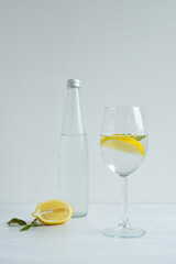 Glass of cold water with lemon and mint standing on the white background