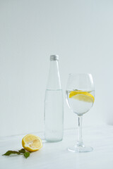 Glass of cold water with lemon and mint standing on the white background