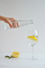 Glass of cold water with lemon and mint standing on the white background