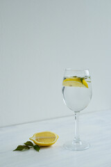 Glass of cold water with lemon and mint standing on the white background