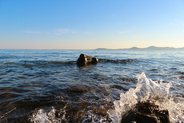 Small wakes splashing the rock stone coast at the dalmatian coast near the town of Pakostane before sunset